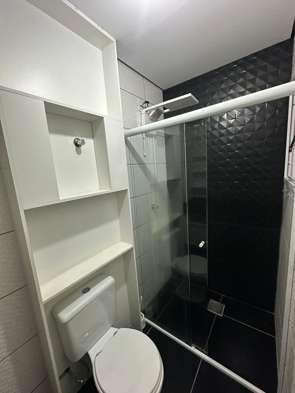 Área do box com revestimento 3D preto, ducha moderna e nicho planejado