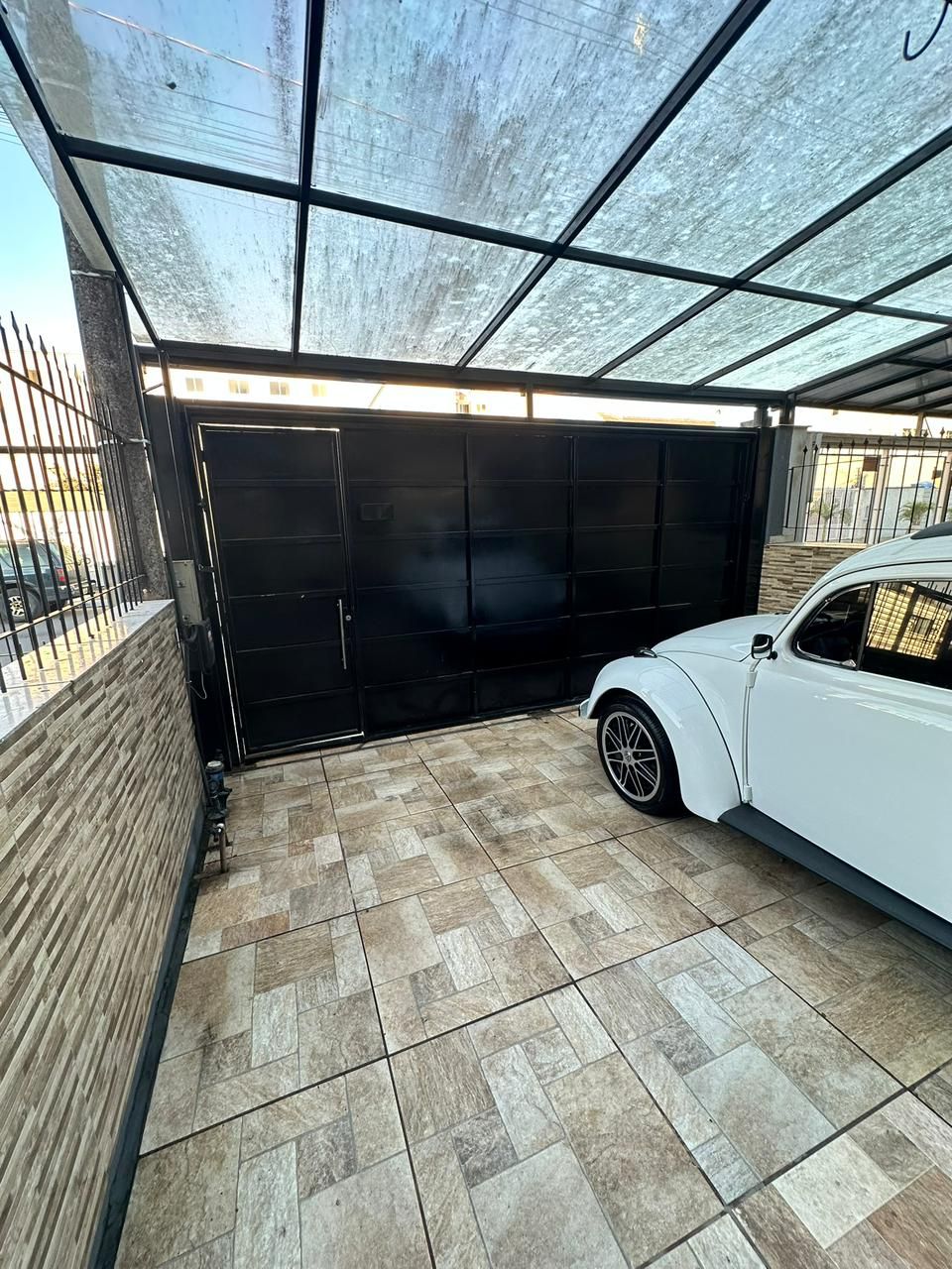 Garagem coberta para carro com portão eletrônico preto