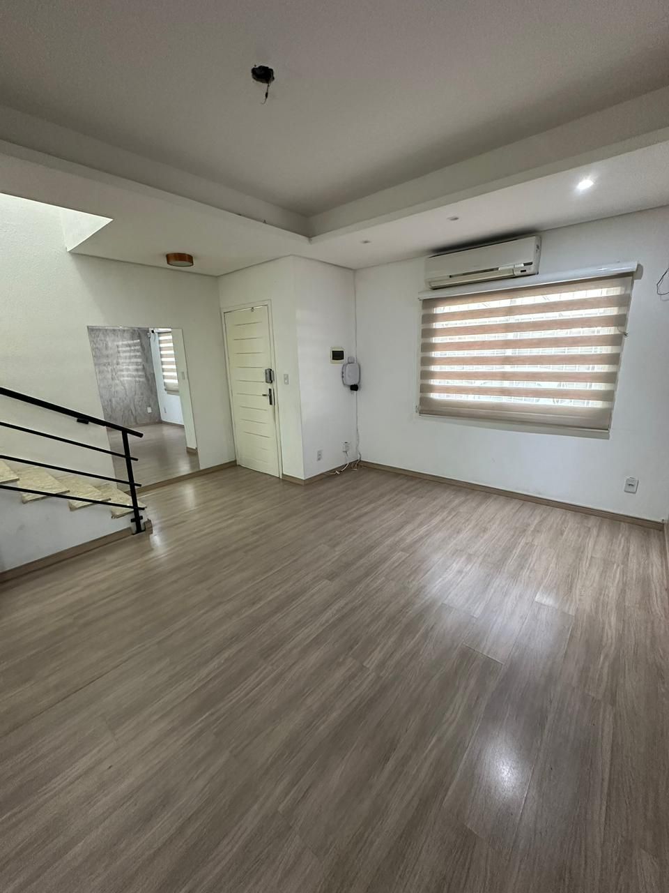 Sala de estar ampla com piso laminado, ar-condicionado e acesso à escada