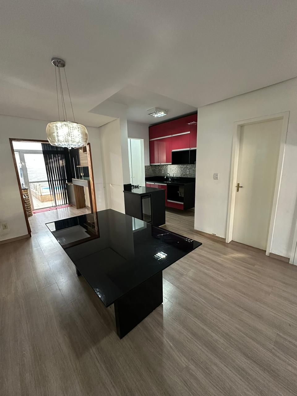 Sala de jantar integrada com lustre de cristal e visão para cozinha e pátio